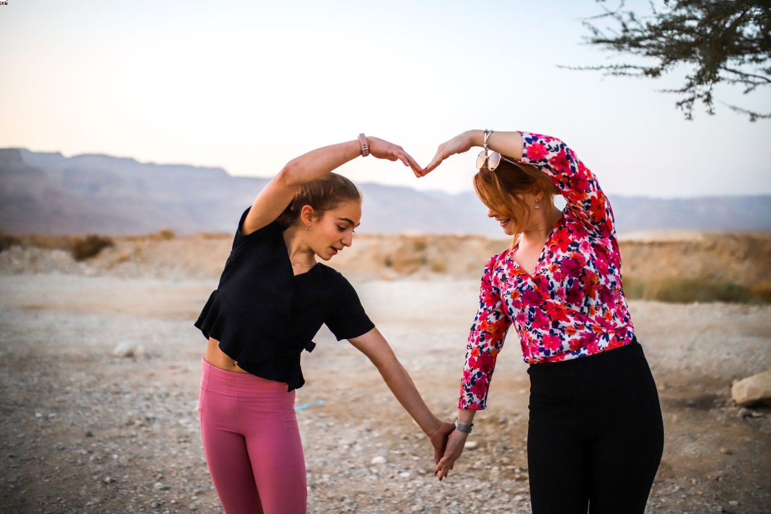 Two people forming heart in desert