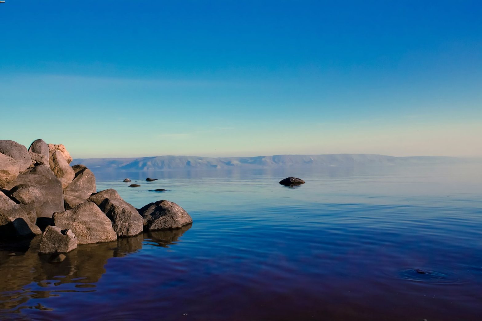 Rocks bordering calm lake at sunrise