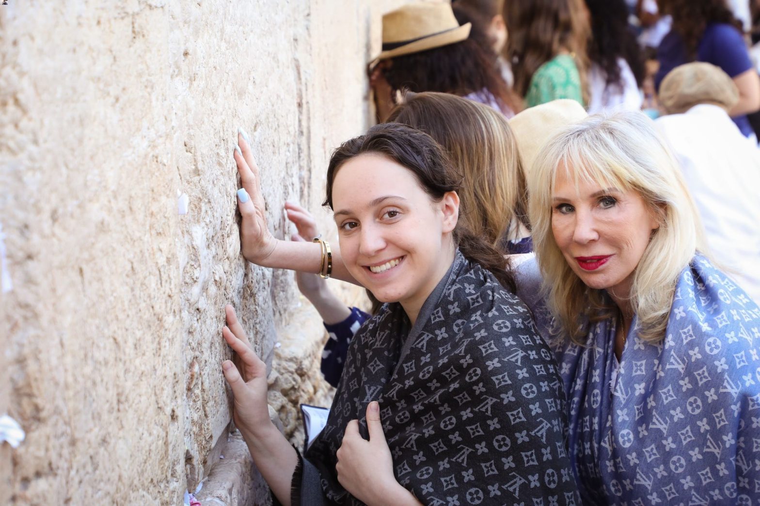 Women touching prayer wall outdoors