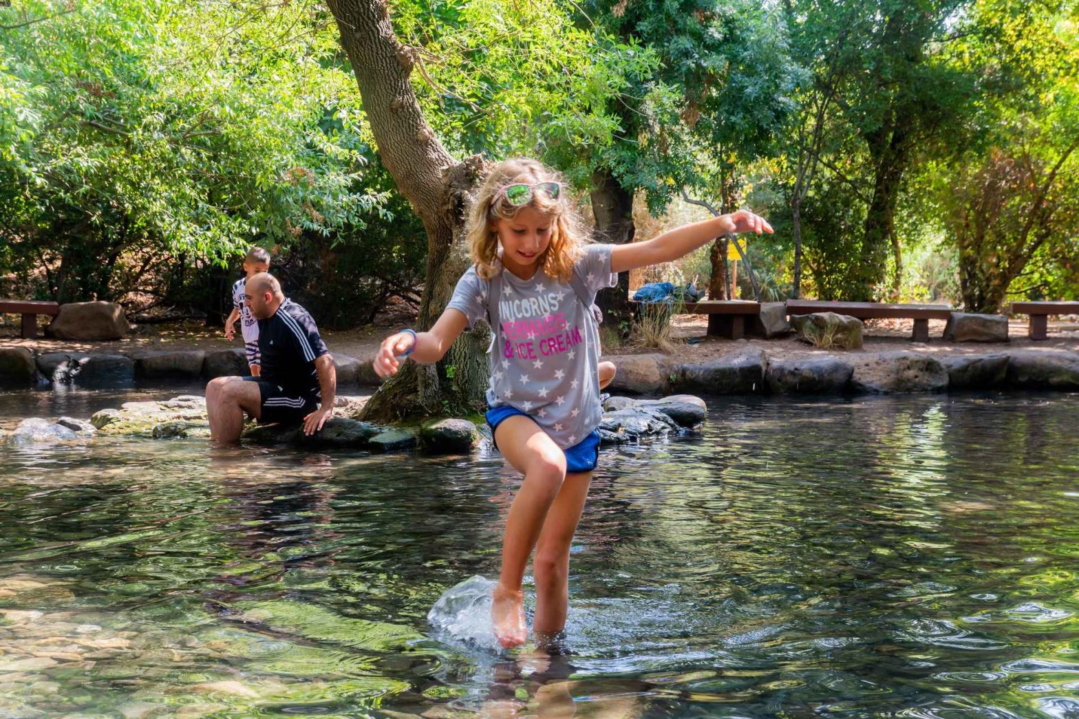 Girl splashing in shallow forest stream